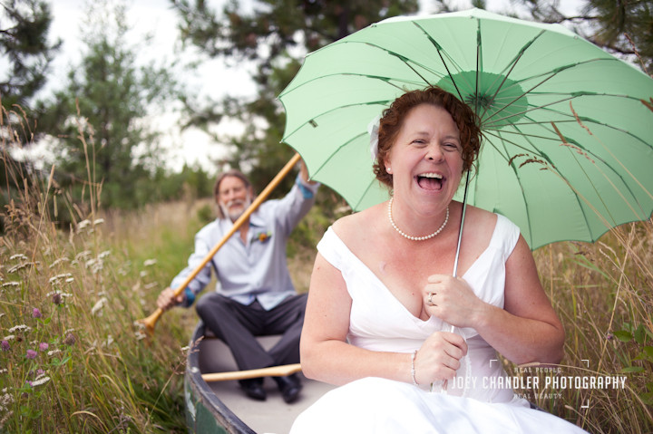 Laughing Bride and Groom row a canoe in grassy field after their wedding vows