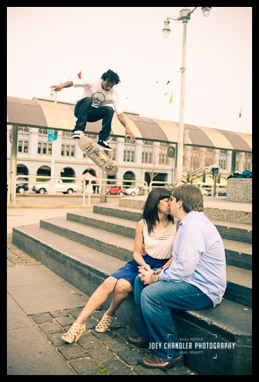 Taking the leap at the Ferry Building Skateboard jumping over kissing couple at Ferry Building- San Francisco Engagement Photographer Joey Chandler