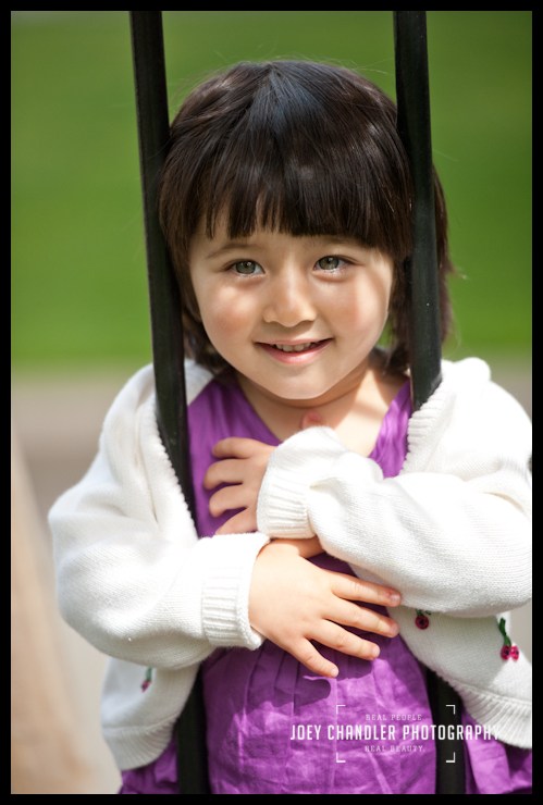 Smiling in the park Girl peeking through a steel fence- San Francisco Child Photography