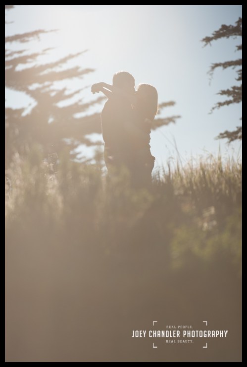 Sunflare at Sunset in San Francisco Couple hugging along San Francisco coast - San Francisco Engagement Photography