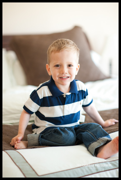 Boy smiling for photographs on bed Boy smiling for photographs on bed