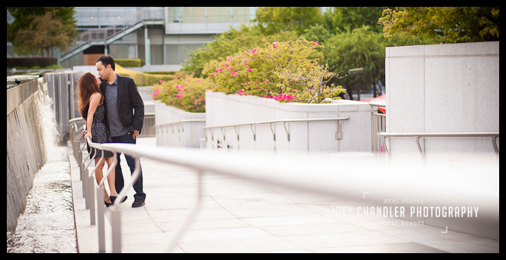 Romantic San Francisco moment in the Yerba Buena Gardens With a fountain behind them and leaning on a railing, a couple looks at each other with passion.
