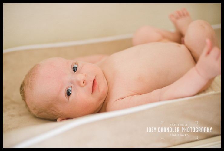 A smiling newborn baby boy Newborn baby boy curled up in a bassinet looking straight at the camera and smiling gently.