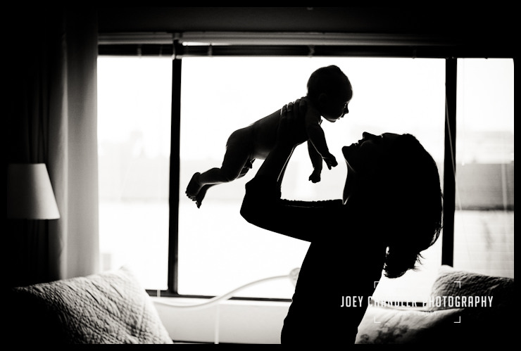 Mother holding here beautiful baby boy Black and white profile of a mother holding her newborn baby in the air just above her face and smiling.