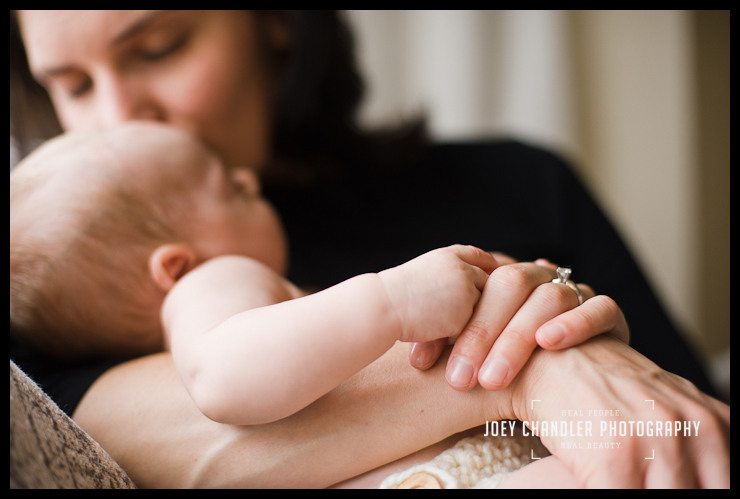 A sweet mother's kiss Mother cradling her newborn baby. He looks away from the camera as she leans down to kiss him.