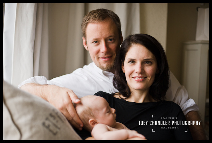 San Francisco Family Portrait Portrait of a family sitting on a cream-colored couch. The father sits in back with his wife leaning against him and their baby sleeping sweetly in her arms.