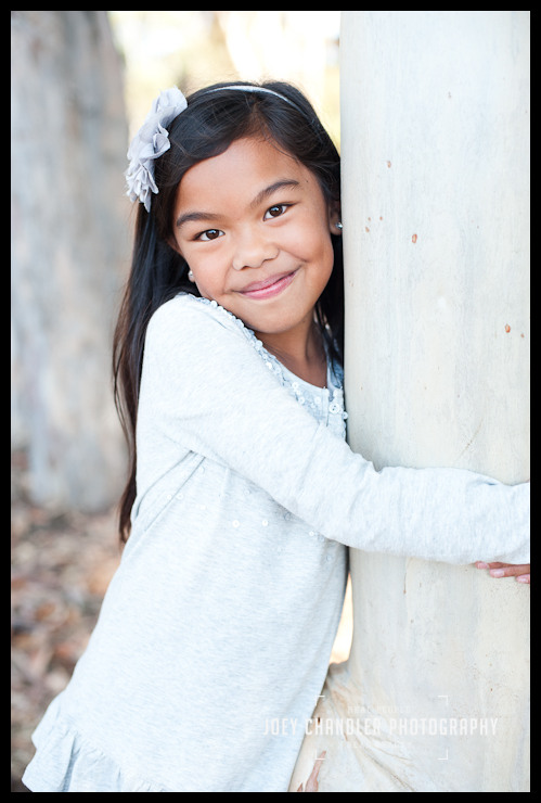Little girl hugging tree trunk at Perry Farms